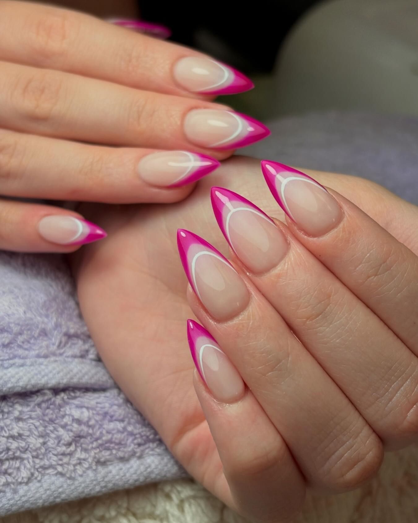 Manos con uñas en forma de stiletto, con puntas francesas con una combinación de colores rosa intenso y blanco.