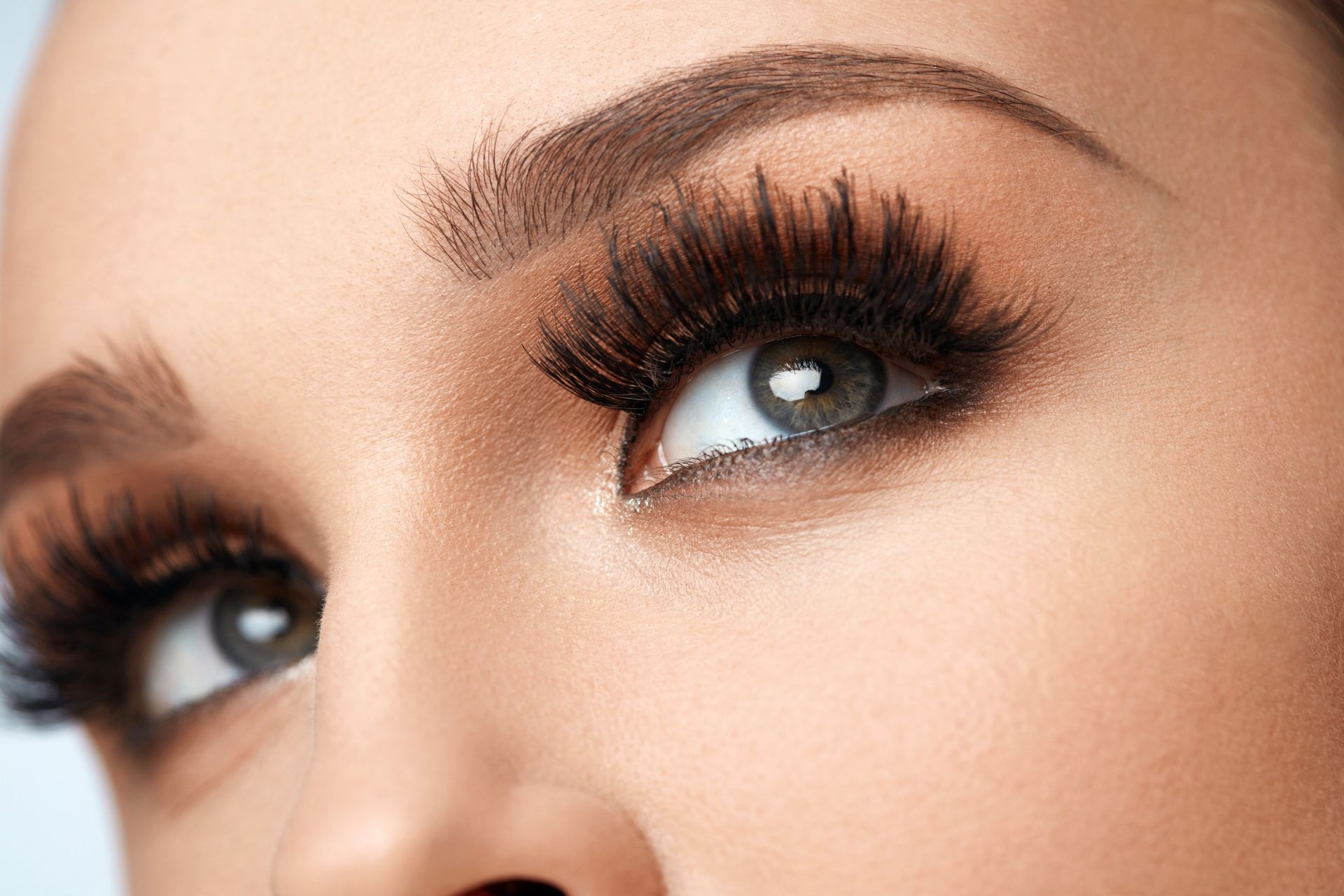 Primer plano de los ojos de una mujer con maquillaje dramático: pestañas oscuras, sombra de ojos ahumada y cejas pobladas.