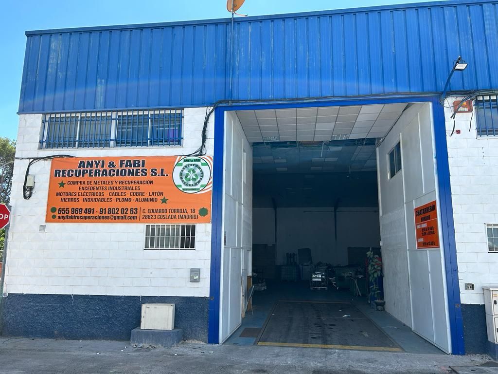 Un centro de reciclaje con fachada azul y blanca. Una gran puerta abierta revela el interior, con un cartel que indica el nombre y los detalles del negocio.