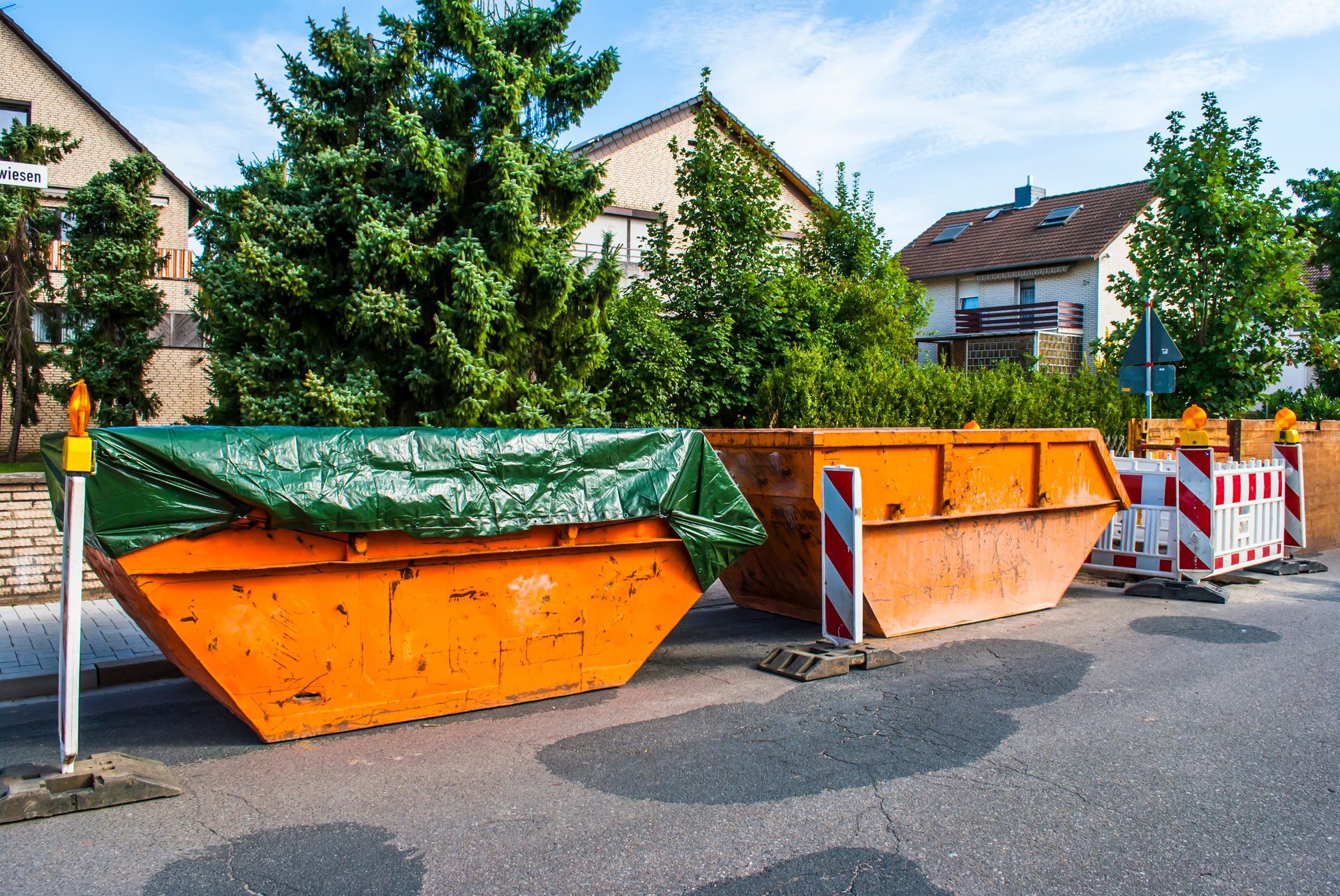 Des bennes à ordures orange dans une rue résidentielle.