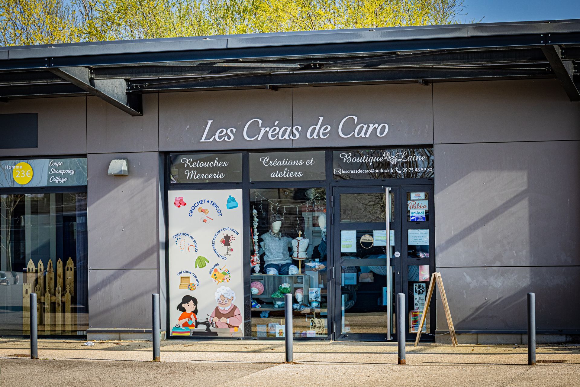 Façade du magasin Les Créas de Caro avec vitrines, façade grise et enseigne dans un cadre extérieur ensoleillé.