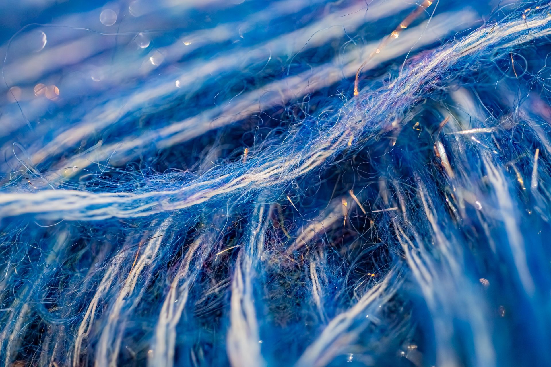 Gros plan, vue macro de brins de fil texturés bleus et blancs, montrant les fibres et les motifs tissés.