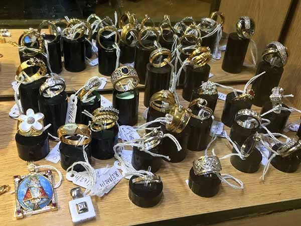 Anillos en expositores negros con etiquetas de precios; vitrina de joyería.