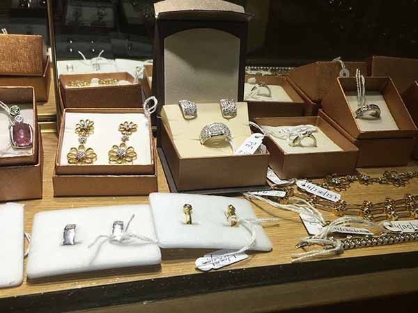 Vitrina de joyería con diversos anillos, pendientes y collares en cajas marrones, con etiquetas de precios.