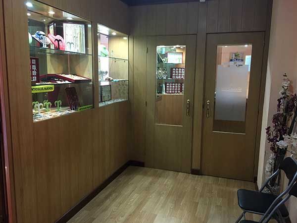 Una entrada con paneles de madera, vitrina de cristal y dos puertas cerradas.