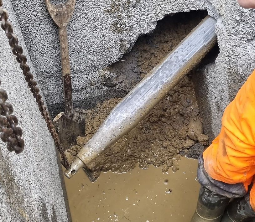 Diagramm eines Strassenbauprojekts. Ein Bohrer bohrt sich unter einer Straße hindurch und ist mit einem Luftkompressor und einem Auto verbunden.