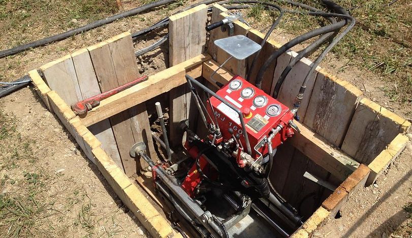 Gelbe Bohrmaschine bohrt sich auf einer Baustelle in felsigen Boden.
