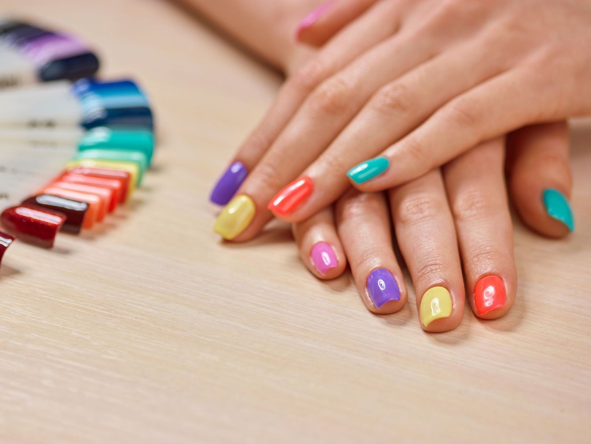 Las uñas de una mujer están pintadas de diferentes colores.