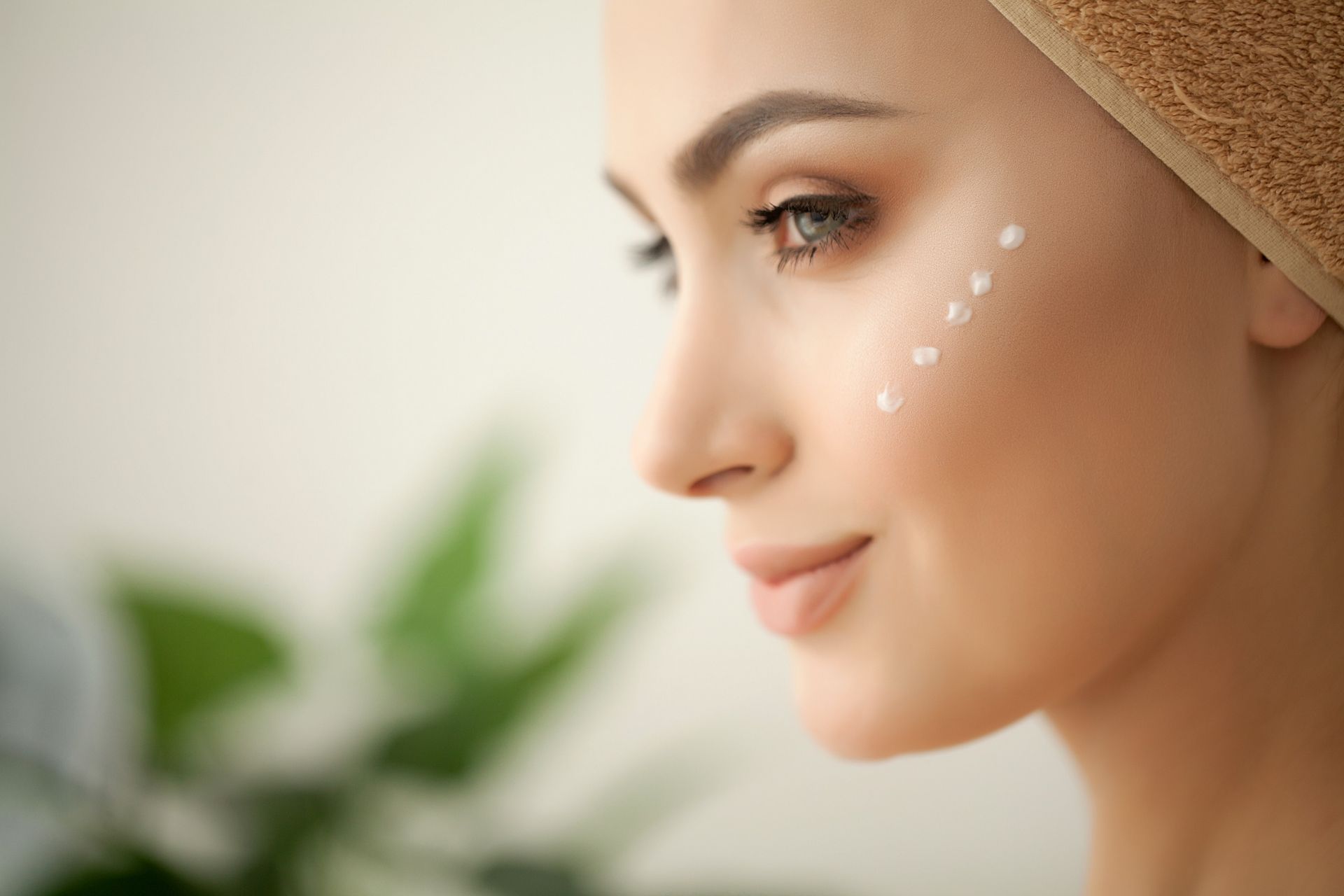 Un primer plano de una mujer aplicándose crema en la cara.