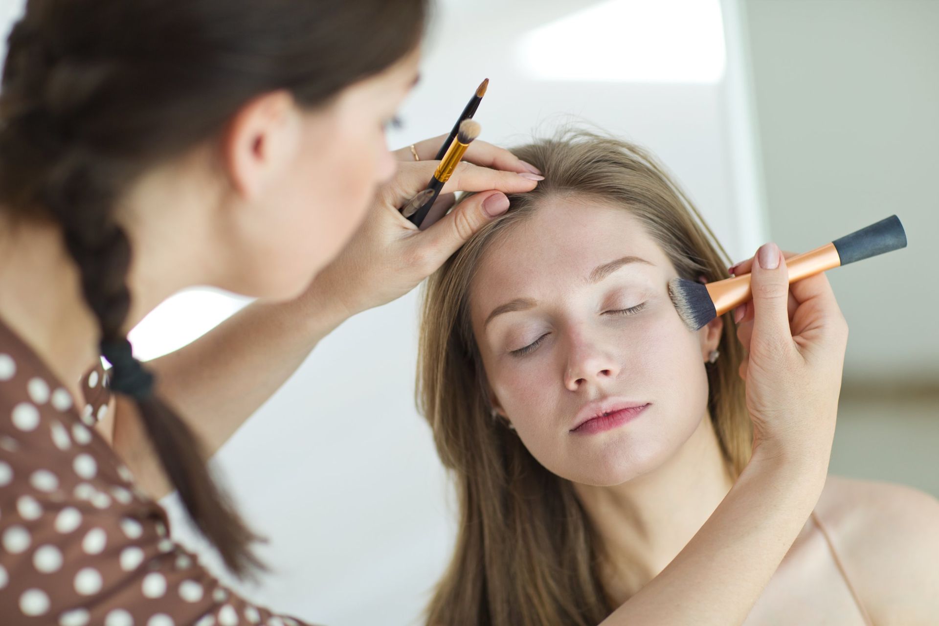 Una mujer está aplicando maquillaje en la cara de otra mujer.
