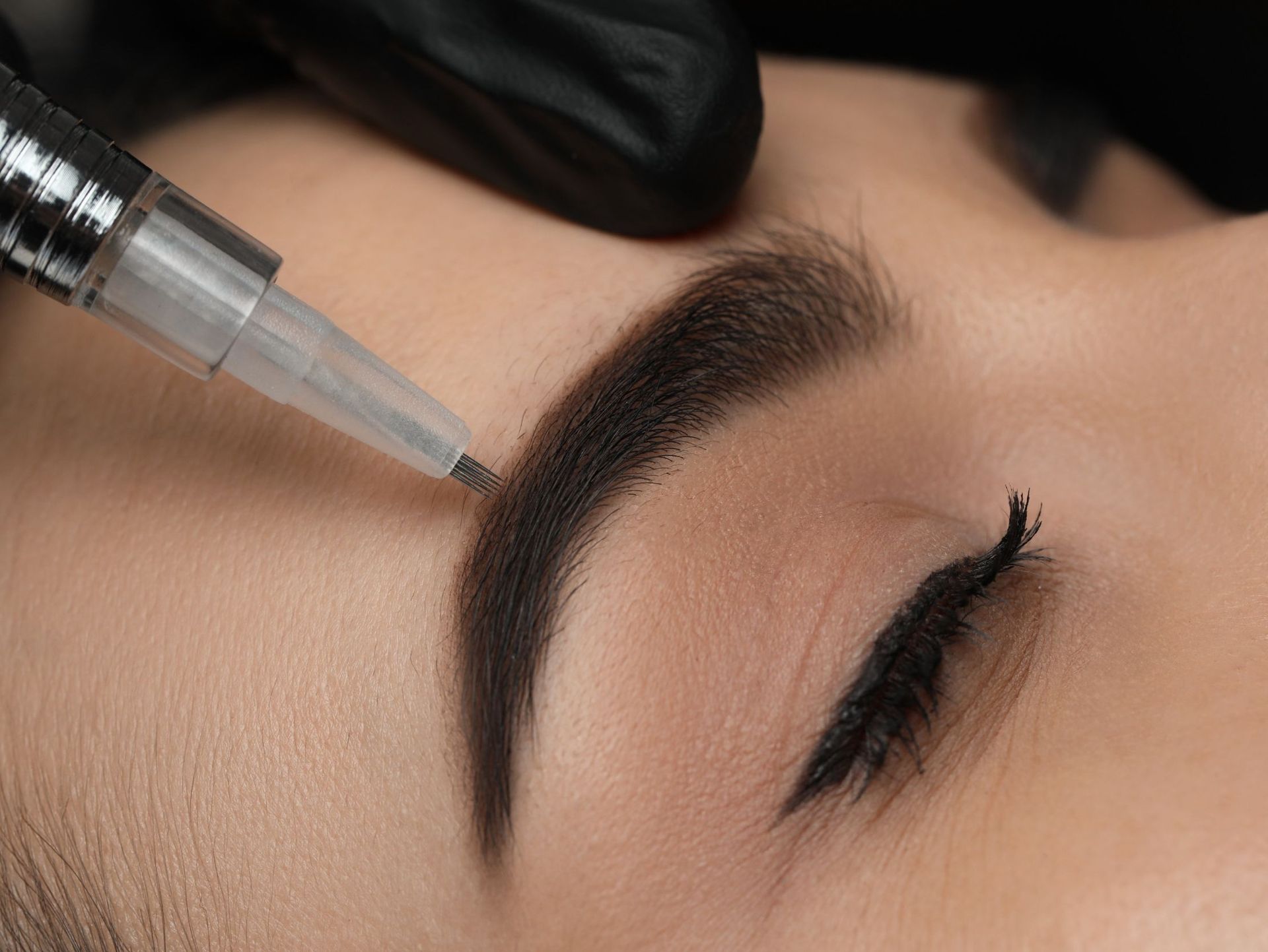 Una mujer se está haciendo un tatuaje de maquillaje permanente en las cejas.