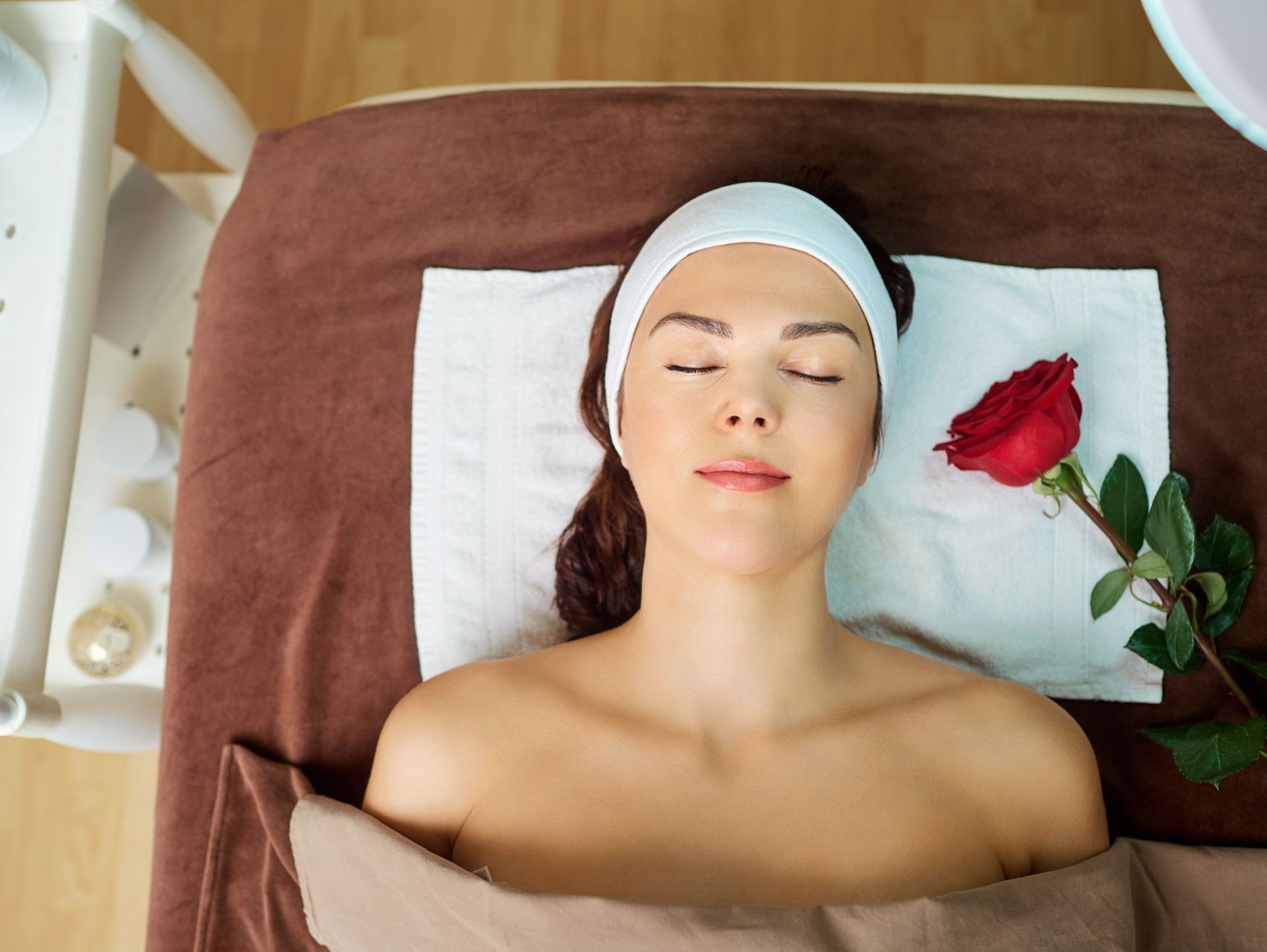 Una mujer está acostada en una cama con los ojos cerrados y una rosa a su lado.