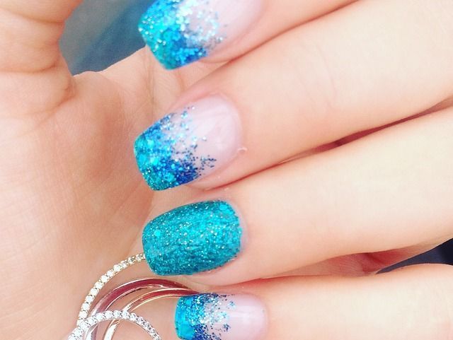 Un primer plano de las uñas de una mujer con un diseño azul y blanco.