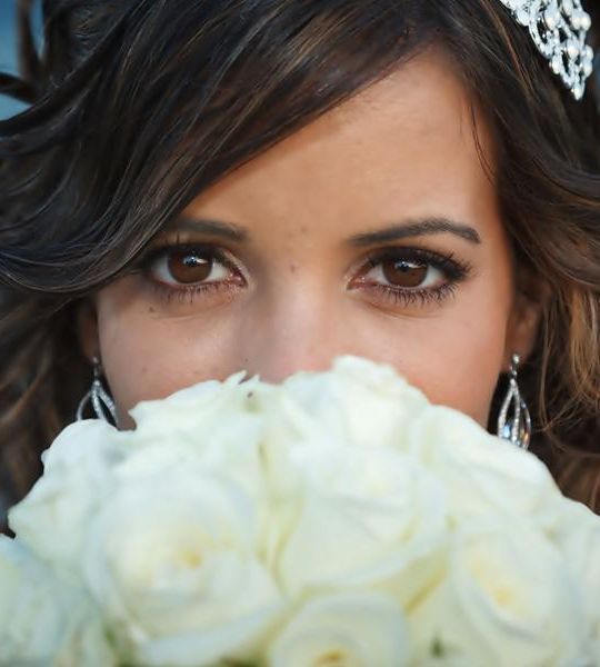 Una mujer cubriéndose la cara con un ramo de rosas blancas.