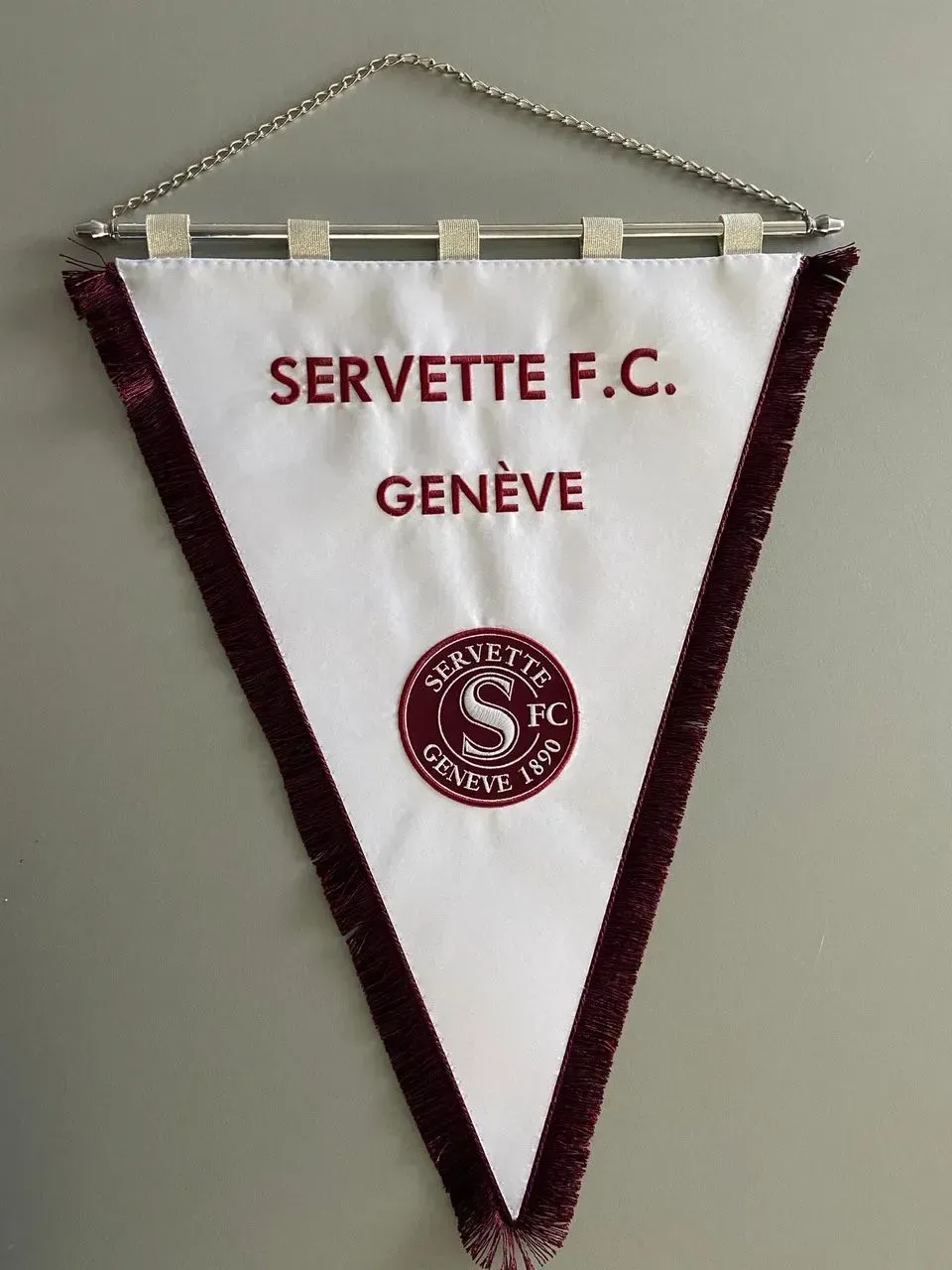 Fanion triangulaire blanc avec bordure bordeaux portant l'inscription « SERVETTE FC GENÈVE » et le logo circulaire du club