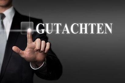 Person im Anzug berührt beleuchteten Text „GUTACHTEN“.