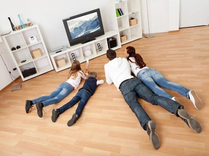 Una familia está tumbada en el suelo viendo la televisión.