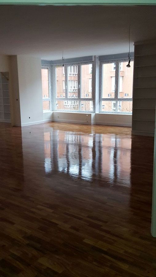 Una gran habitación vacía con pisos de madera y muchas ventanas.