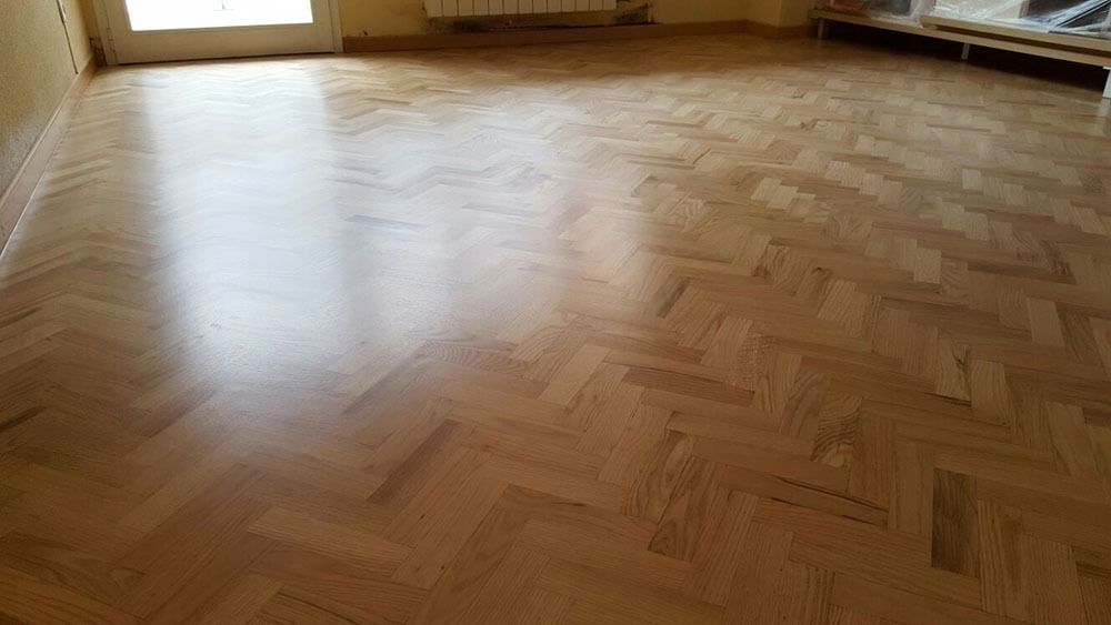 Un suelo de madera en una sala de estar con diseño de espiga.