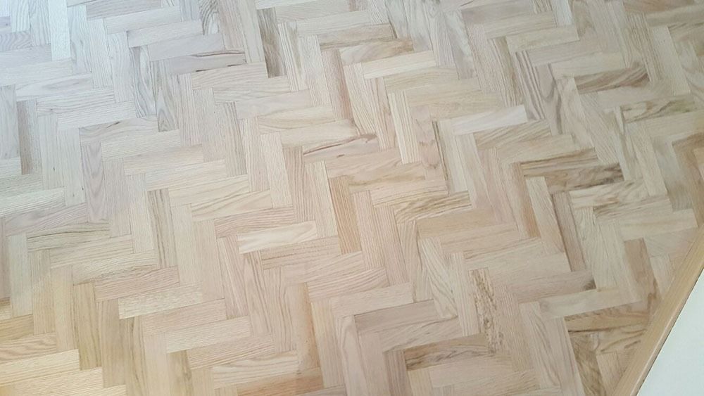 Un primer plano de un piso de madera con patrón de espiga.