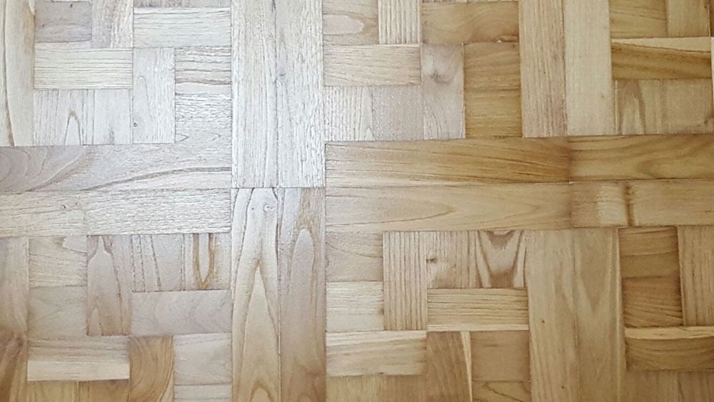 Un primer plano de un piso de madera con un patrón de tejido.