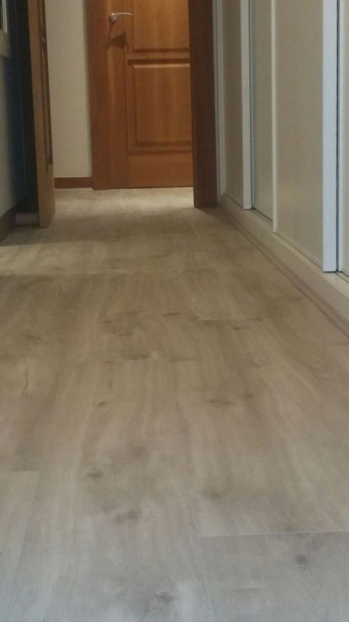 Un pasillo con suelo de madera y una puerta de madera.