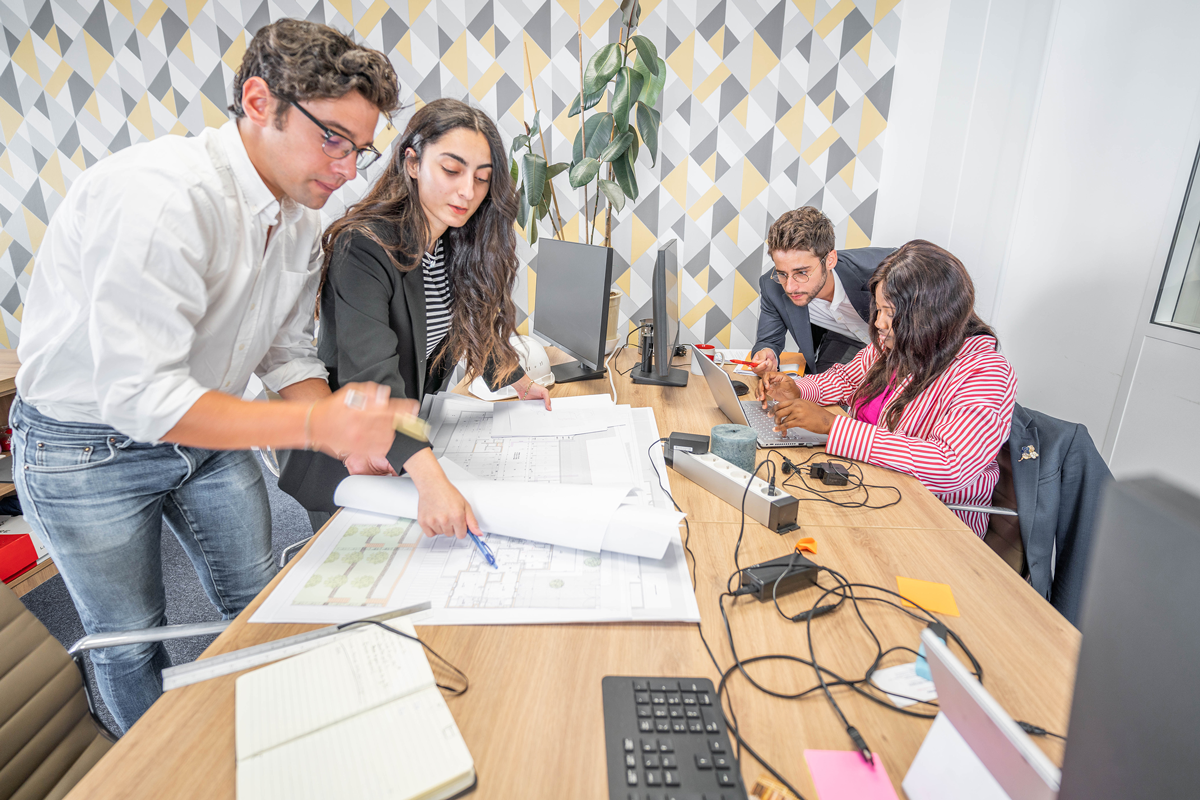Plusieurs personnes de chez bexconsult, étudiant des plans disposés sur le bureau