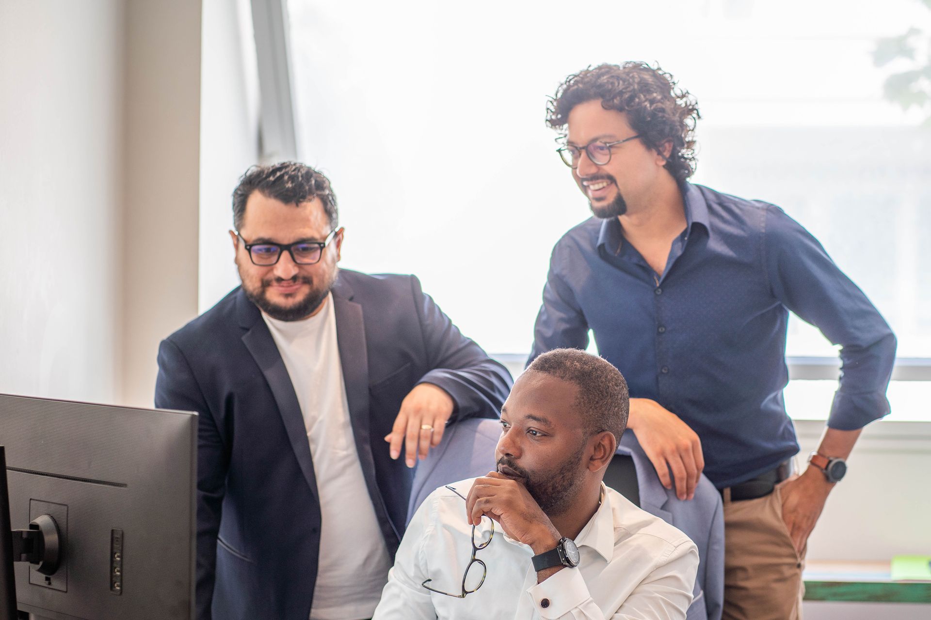 Trois hommes de bexconsult en chemise et veste regardant l'écran d'un ordinateur