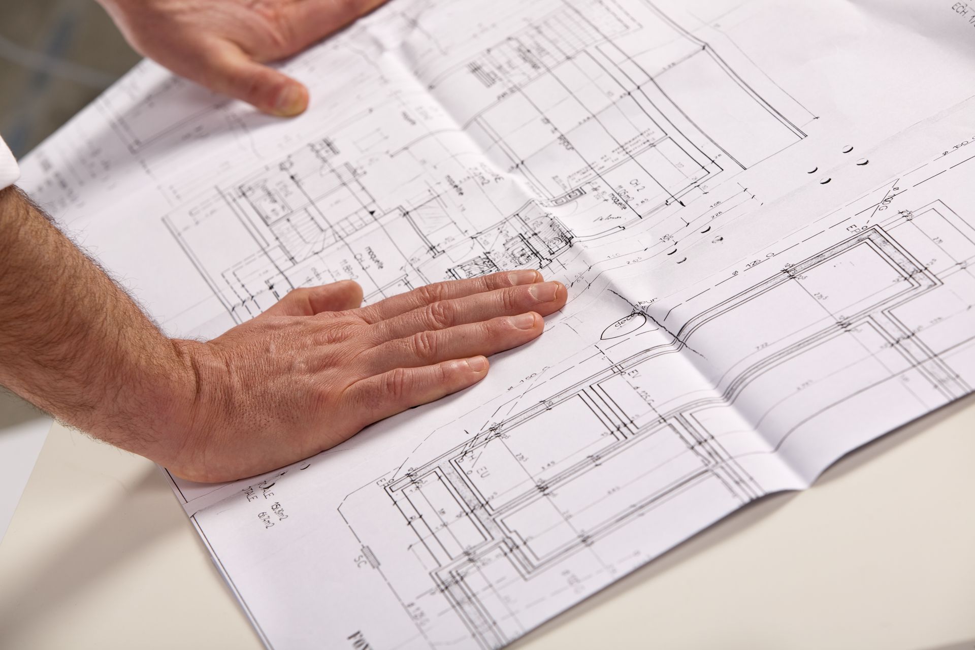 Mains posées à plat sur un plan de construction