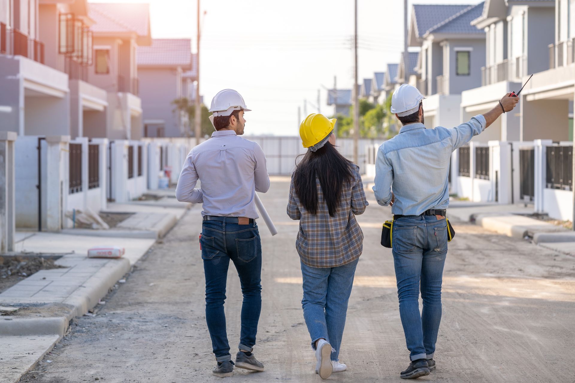 Trois personnes de dos avec des casque de chantier sur un chantier de lotissements