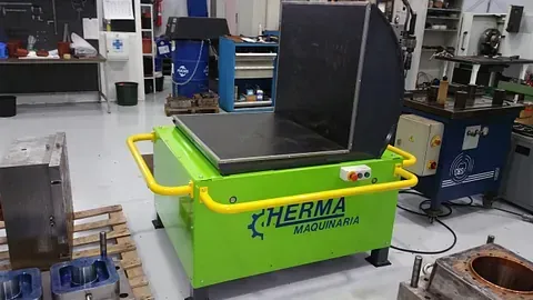 Una máquina verde está sentada encima de una mesa en una fábrica.