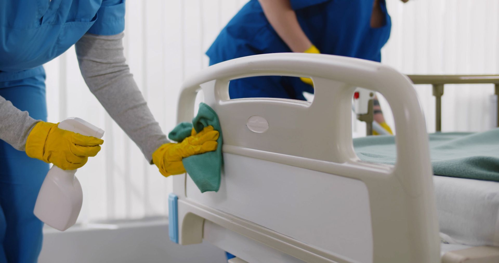Eine Person mit blauen Handschuhen reinigt eine Operationsleuchte