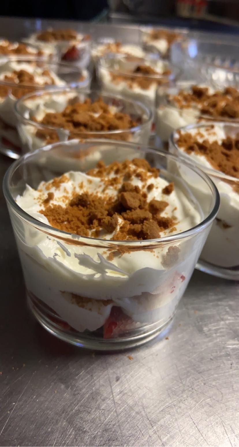Des verrines garnies de couches de crème, de fraises et de biscuits émiettés.