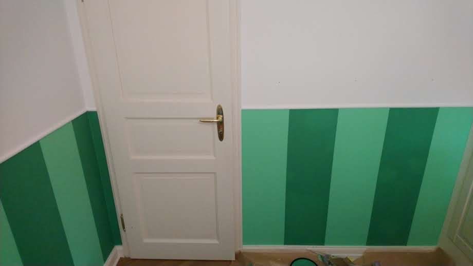 Ein Raum mit grün-weiß gestreiften Wänden und einer weißen Tür.