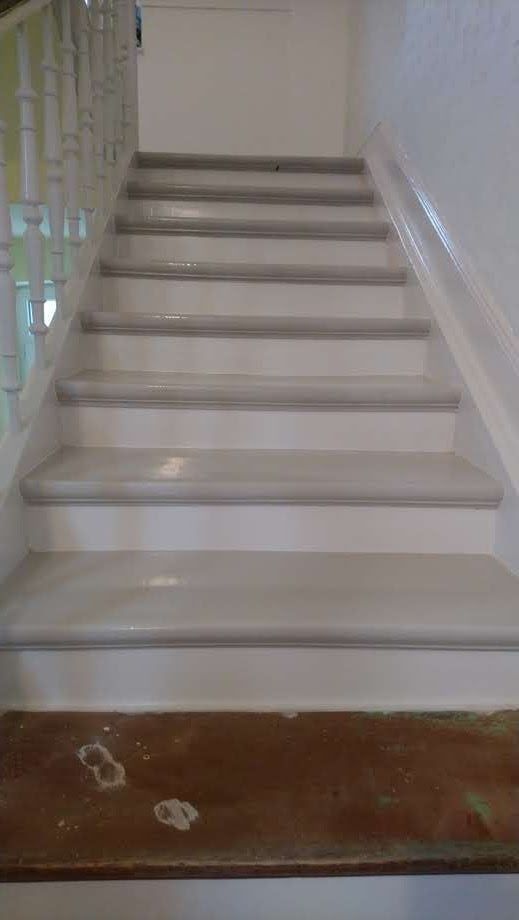 Eine Nahaufnahme einer weißen Treppe mit einem Holzgeländer.