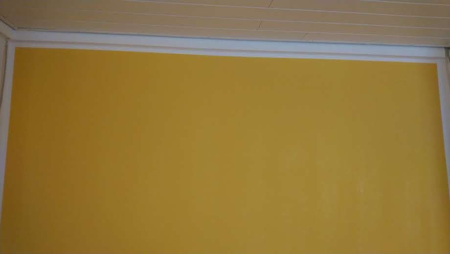 Eine gelbe Wand mit weißen Zierleisten und einer weißen Decke in einem Raum.