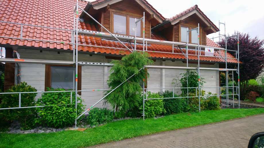 Ein Haus mit einem Gerüst an der Seite und einem davor geparkten Auto.