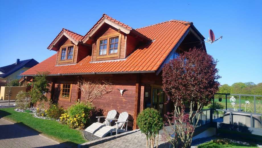 Ein Haus mit einem roten Ziegeldach und einem Vogel, der am Himmel fliegt