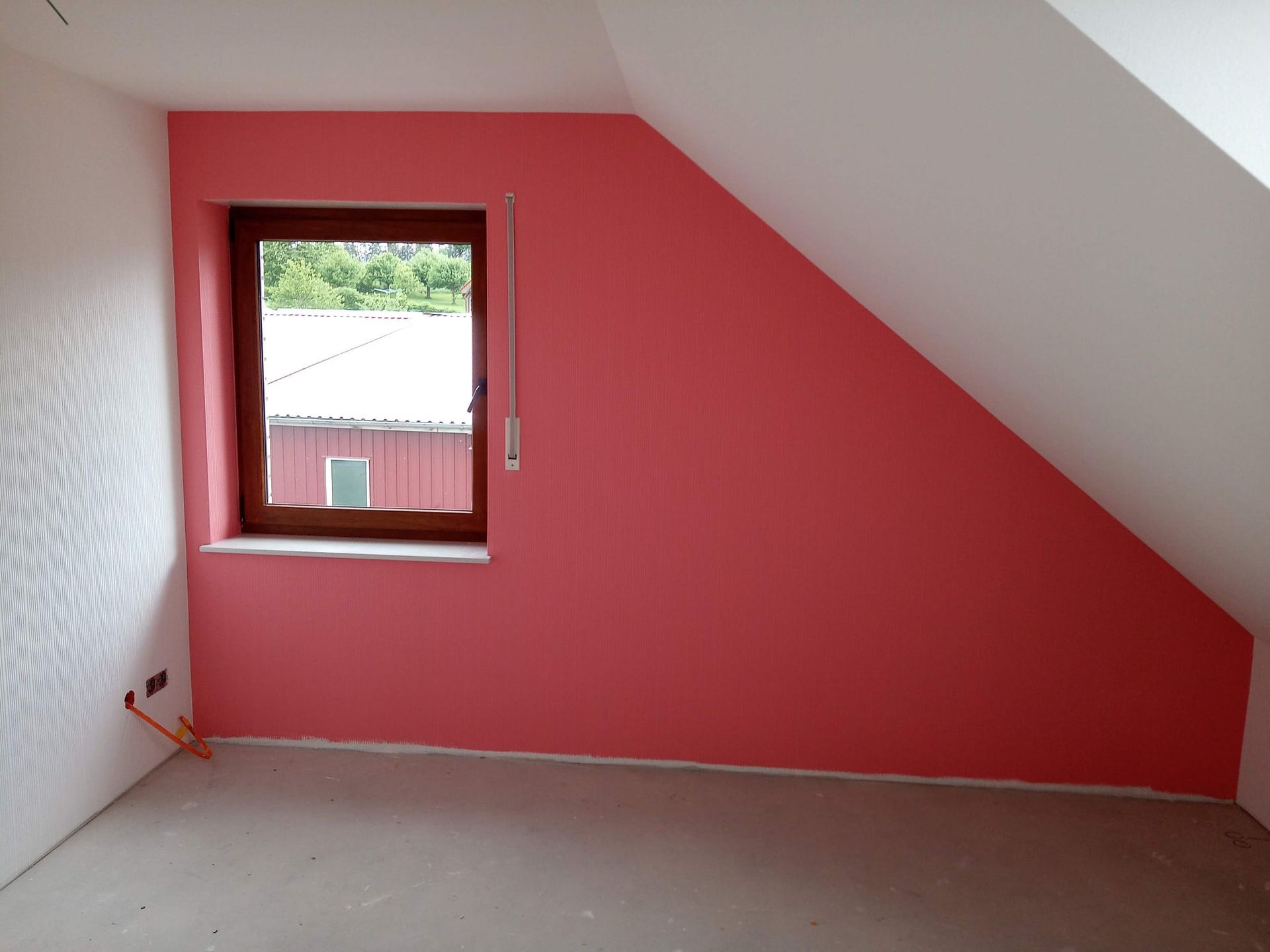 Ein leerer Raum mit einer rosa Wand und einem Fenster