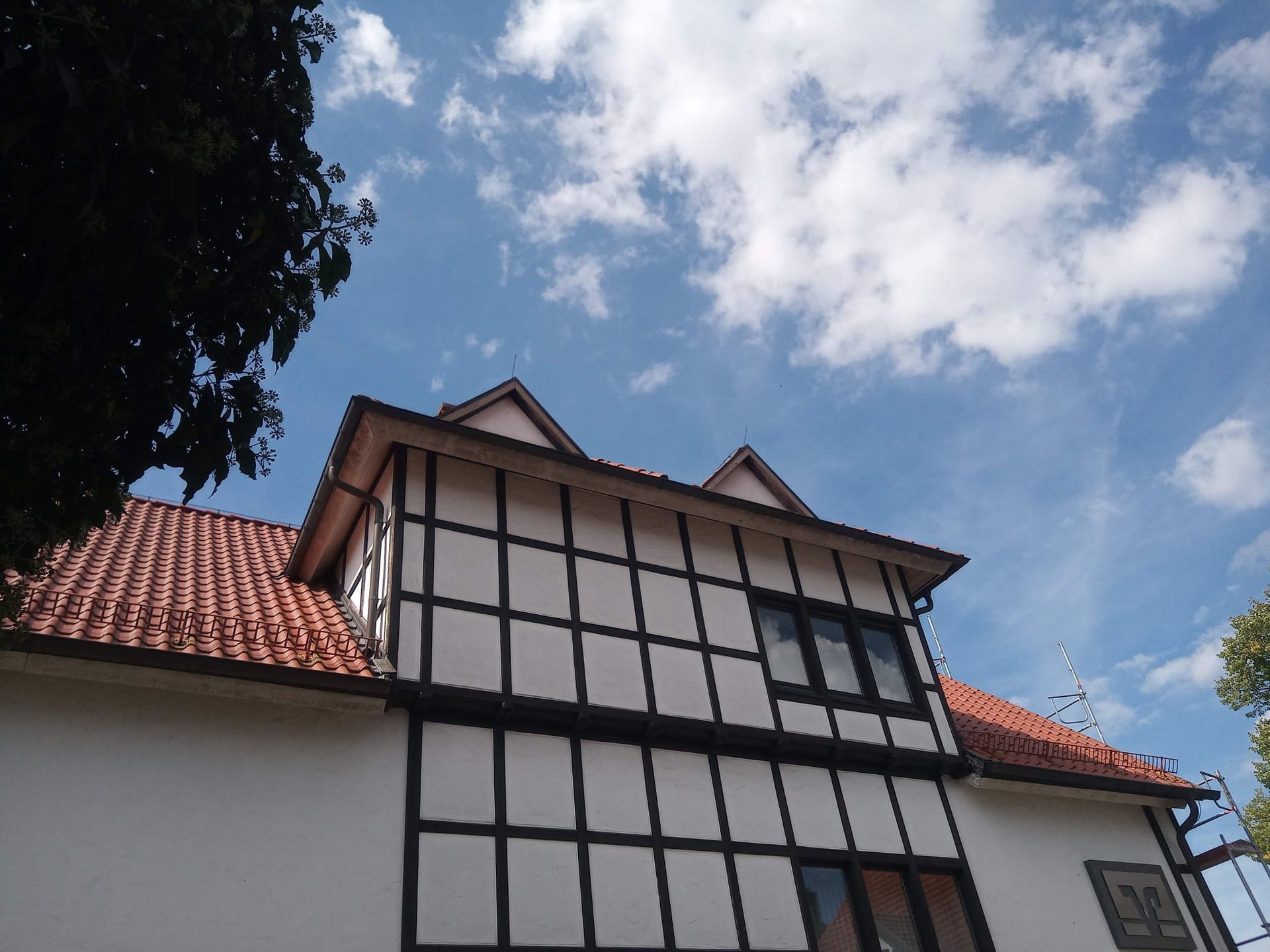 Blick nach oben auf ein Haus mit blauem Himmel und Wolken dahinter