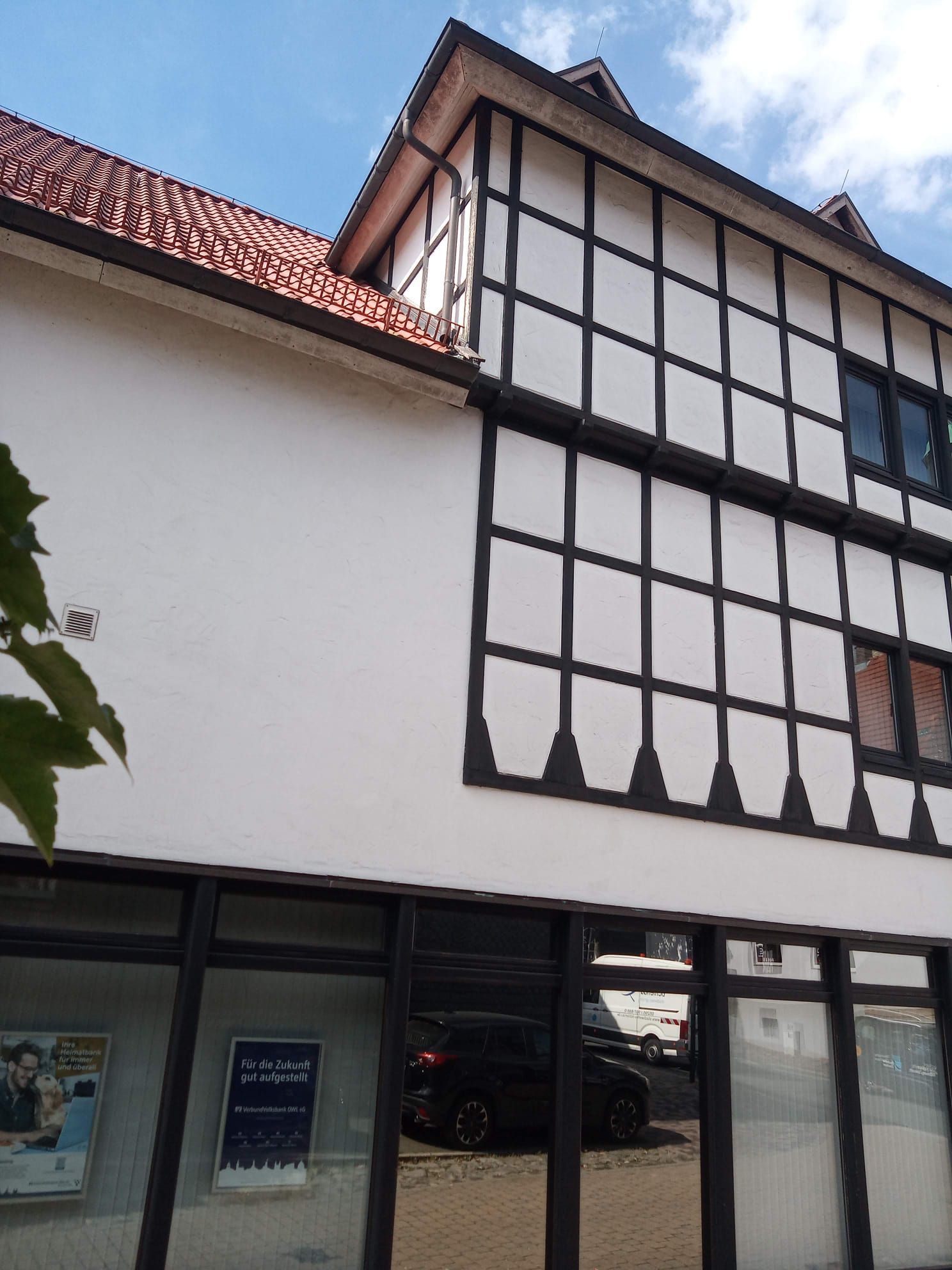 Ein weiß-schwarzes Gebäude mit einem davor geparkten Auto