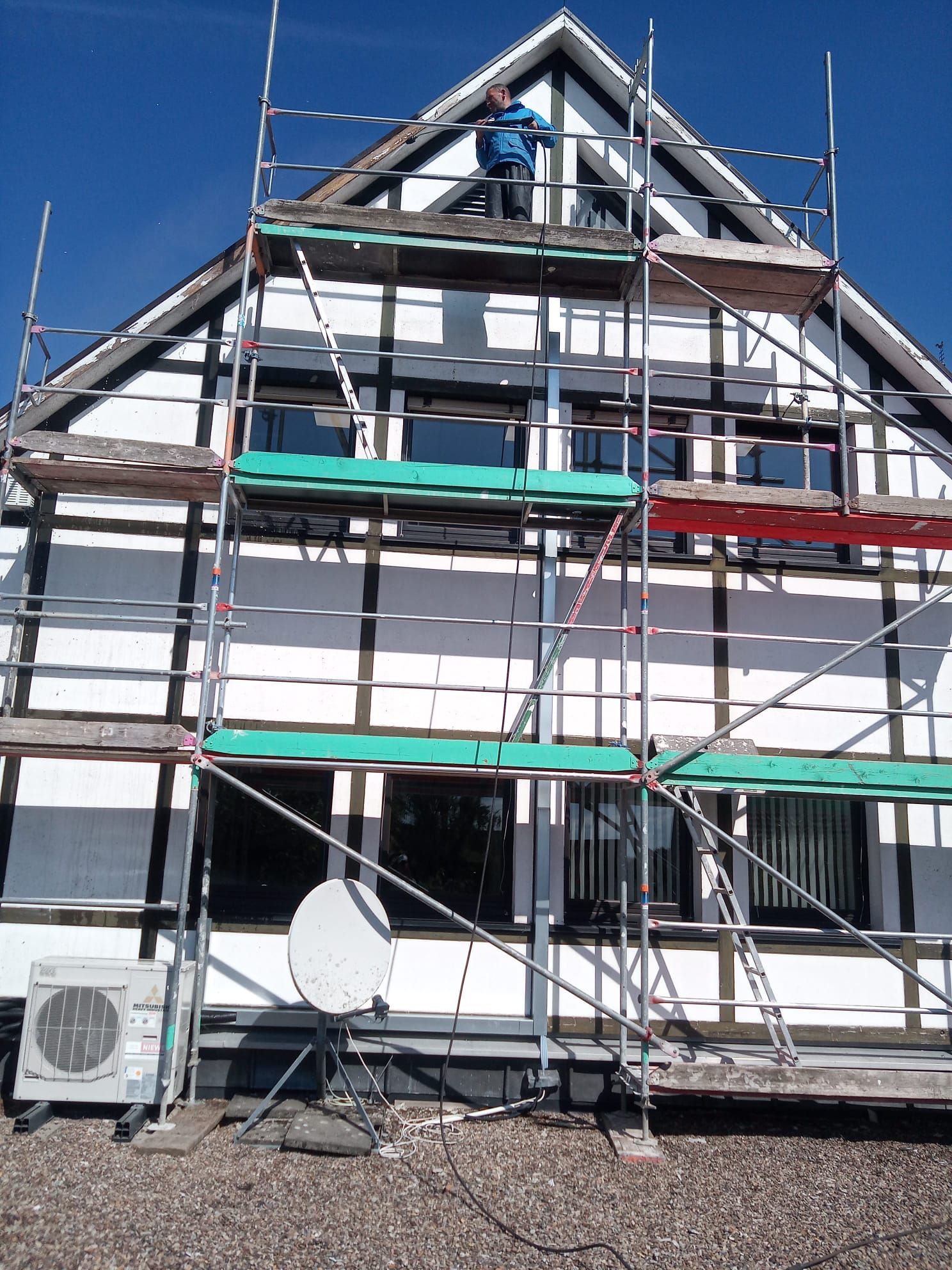 Ein Mann steht auf einem Gerüst auf einem Gebäude.