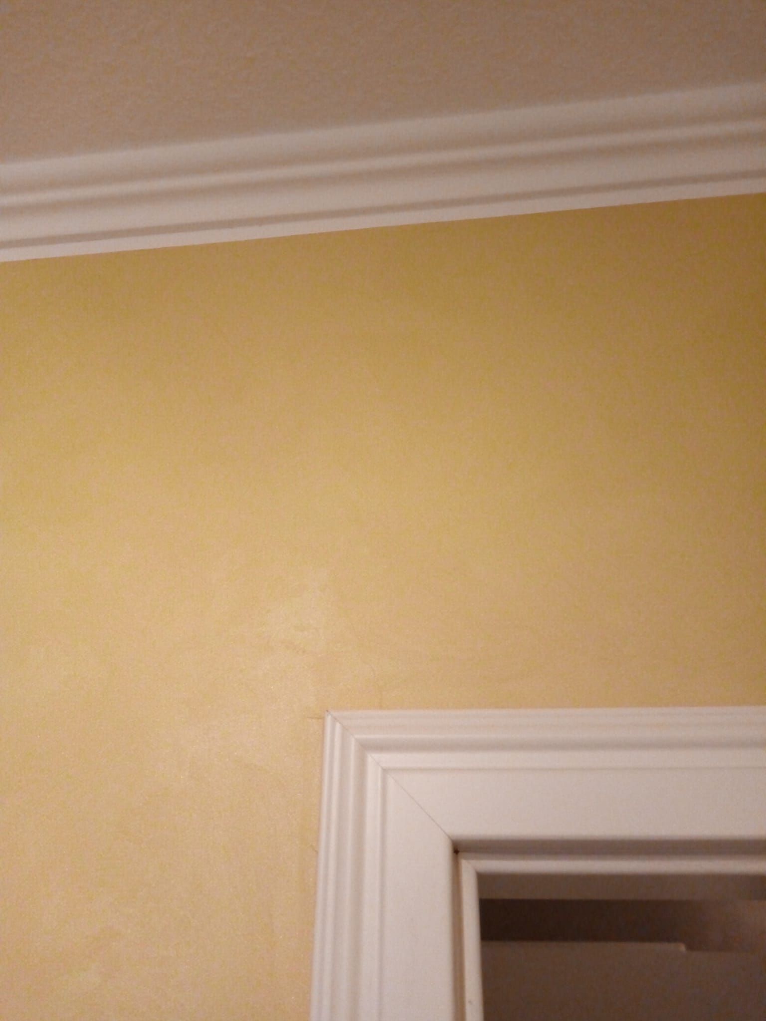 Eine Nahaufnahme einer Tür mit einer gelben Wand und weißen Verzierungen.