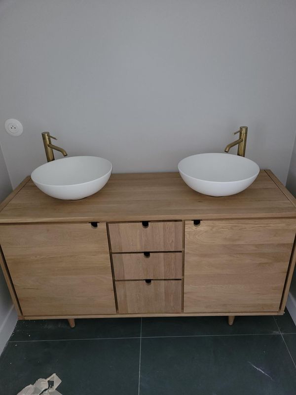 Meuble sous lavabo moderne à double vasque avec deux vasques blanches et armoire en bois dans une salle de bains.