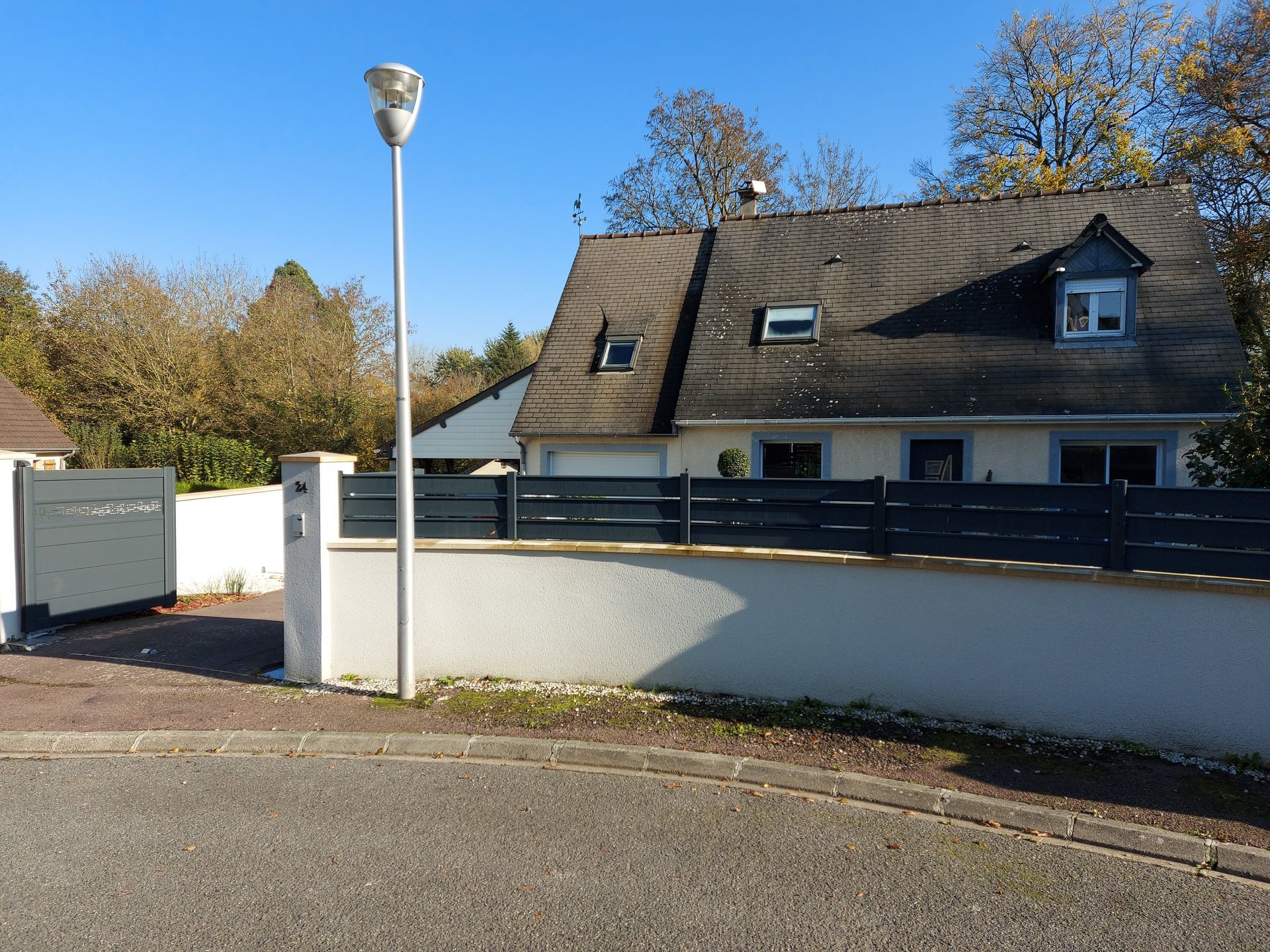 Une maison avec une clôture et un lampadaire