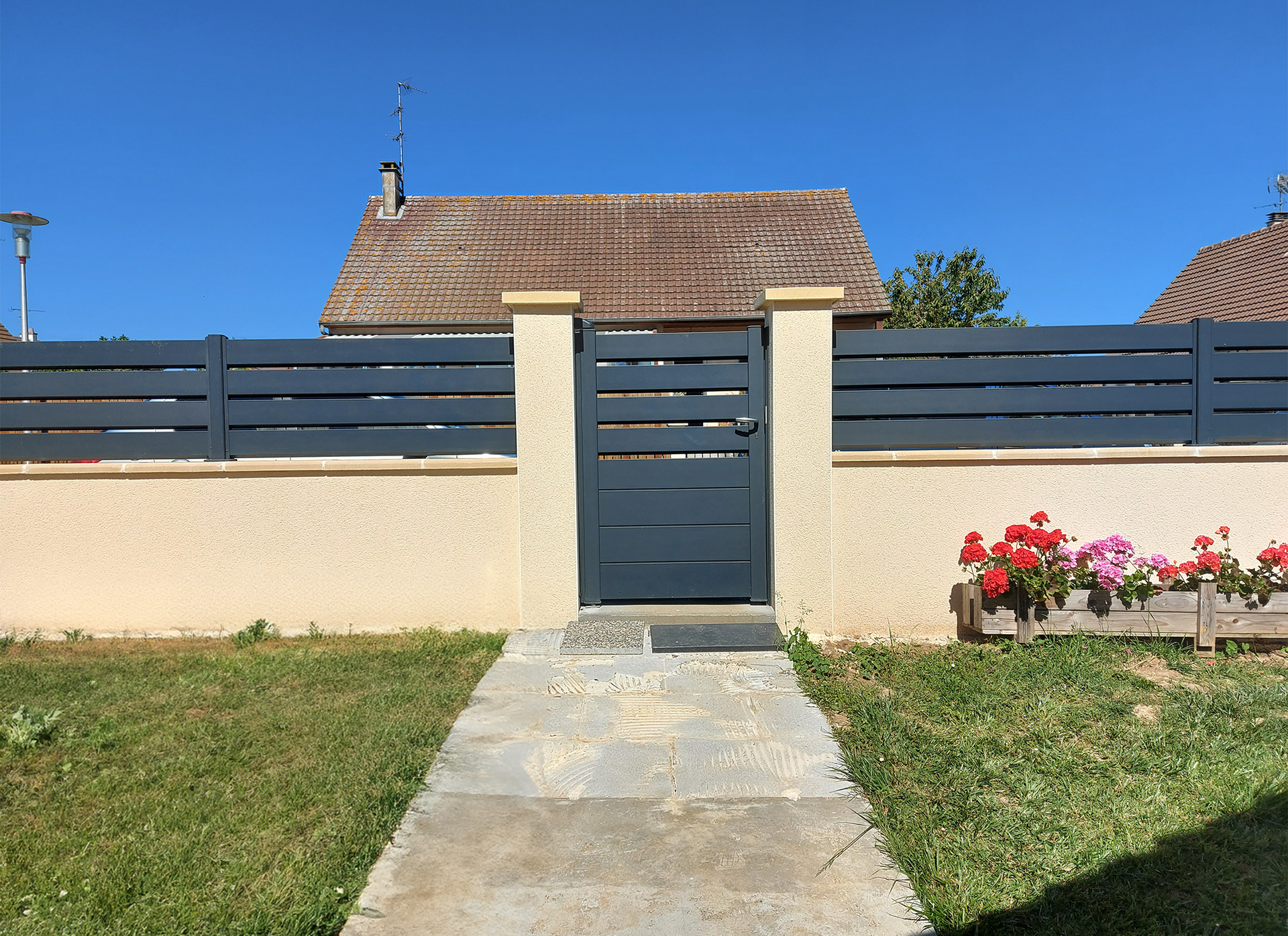 Une maison avec une clôture et des fleurs dans la cour