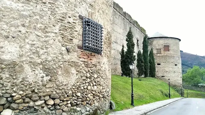 Un muro de piedra con una ventana y un castillo al fondo.