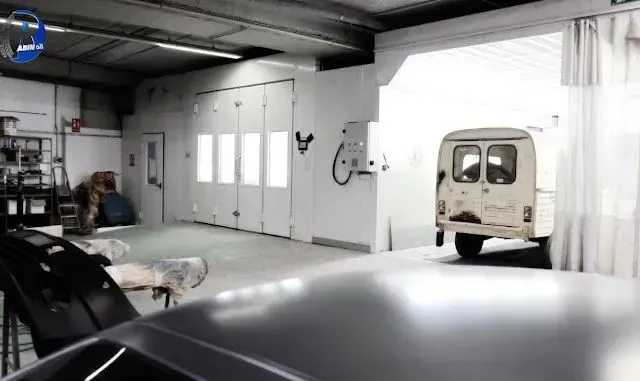 Un coche está estacionado en un garaje al lado de una furgoneta.