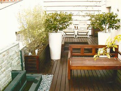 Aménagement d'un balcon avec plantes vertes et sièges en bois