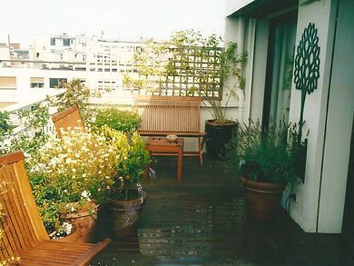 Balcon aménagé avec des plantes et assises en bois